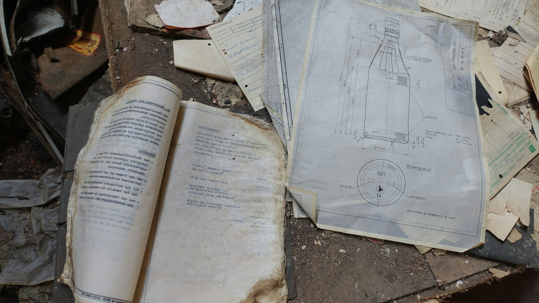In einer Baracke neben den Lagerhallen liegen auf dem Boden historische technische Zeichnungen.