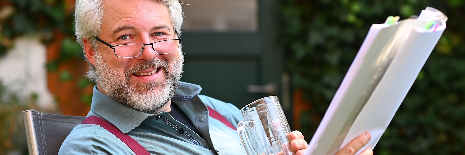 „Rosenheim-Cops“-Schauspieler Dieter Fischer sitzt mit einem Drehbuch und einer Saftschorle in seinem Garten im bayerischen Pöcking.