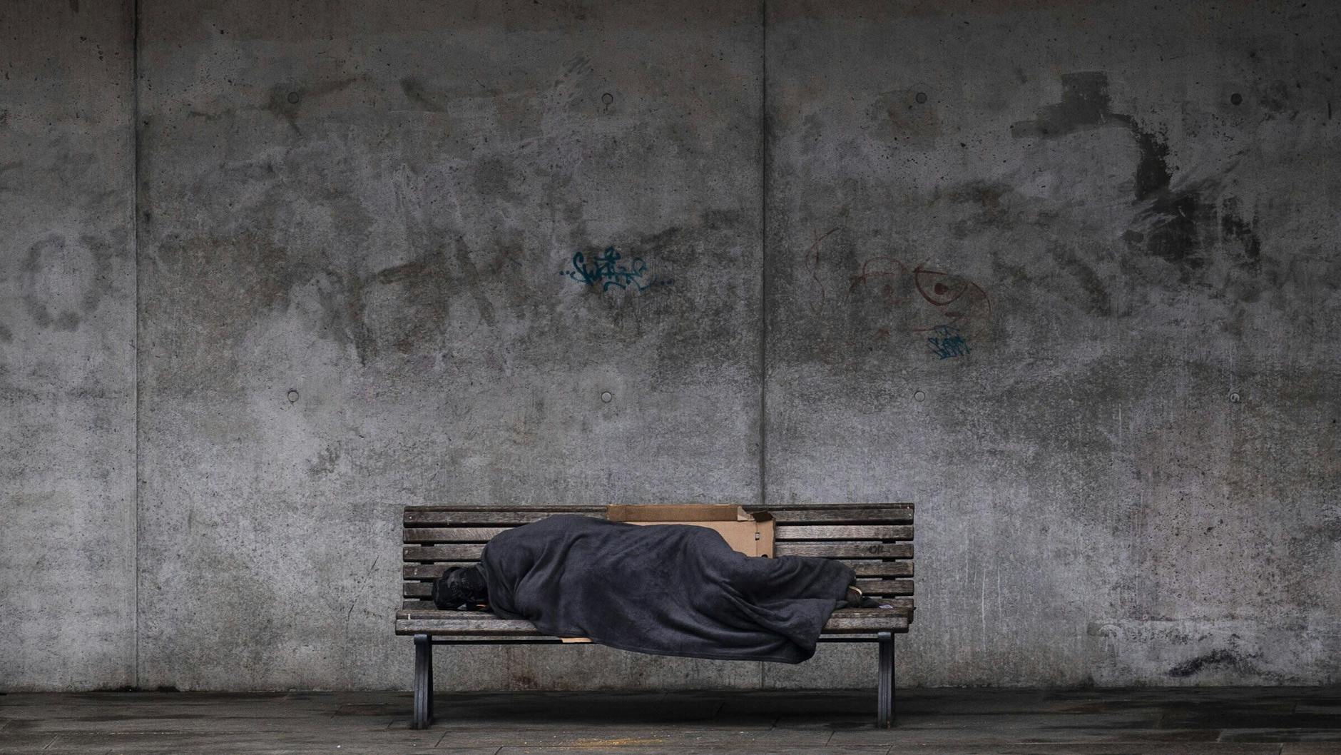Ein Obdachloser schläft auf einer Bank (Symbolbild).
