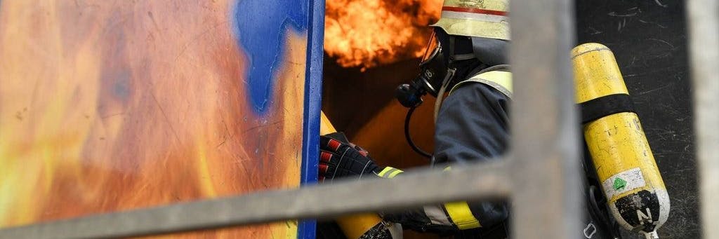 Ein Feuerwehrmann betritt unter Atemschutz eine brennende Wohnung (Symbolbild).