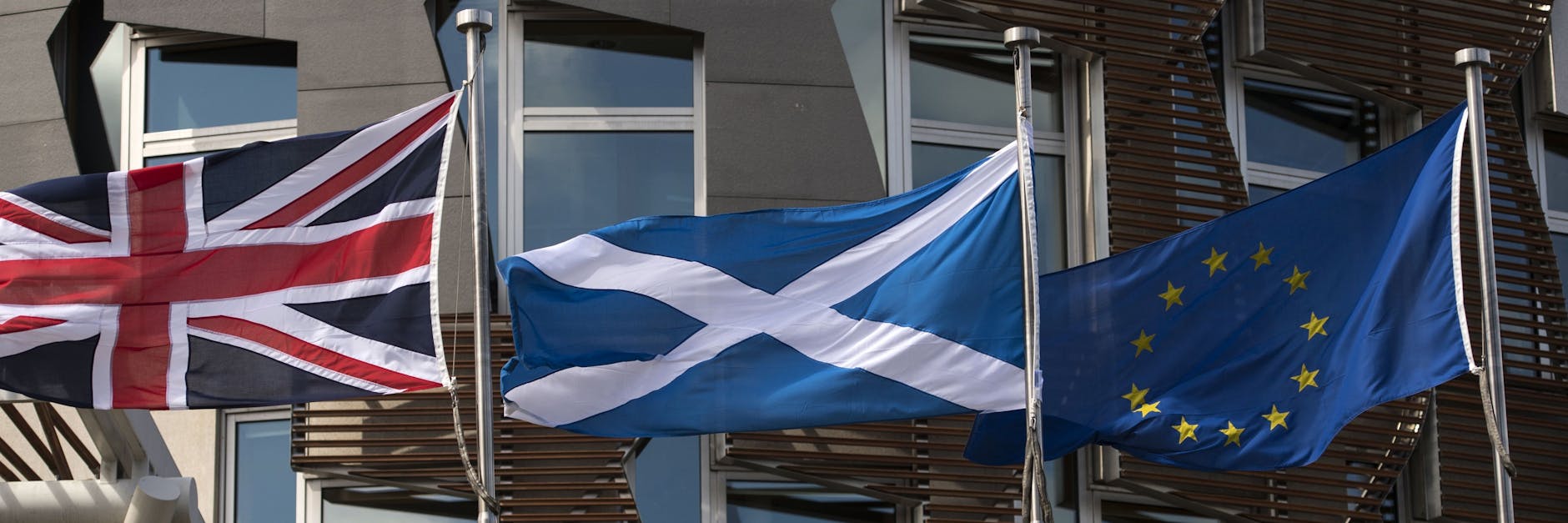 Die schottische Fahne in der Mitte weht vor dem Regionalparlament in Edinburgh zwischen dem britischen Union Jack und der EU-Flagge.