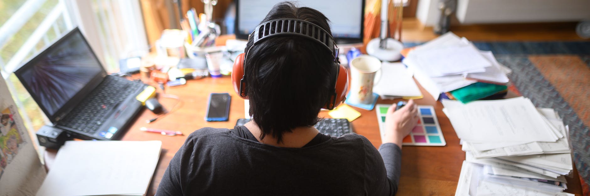 Eine Frau arbeitet mit Hörschutz im Homeoffice. 