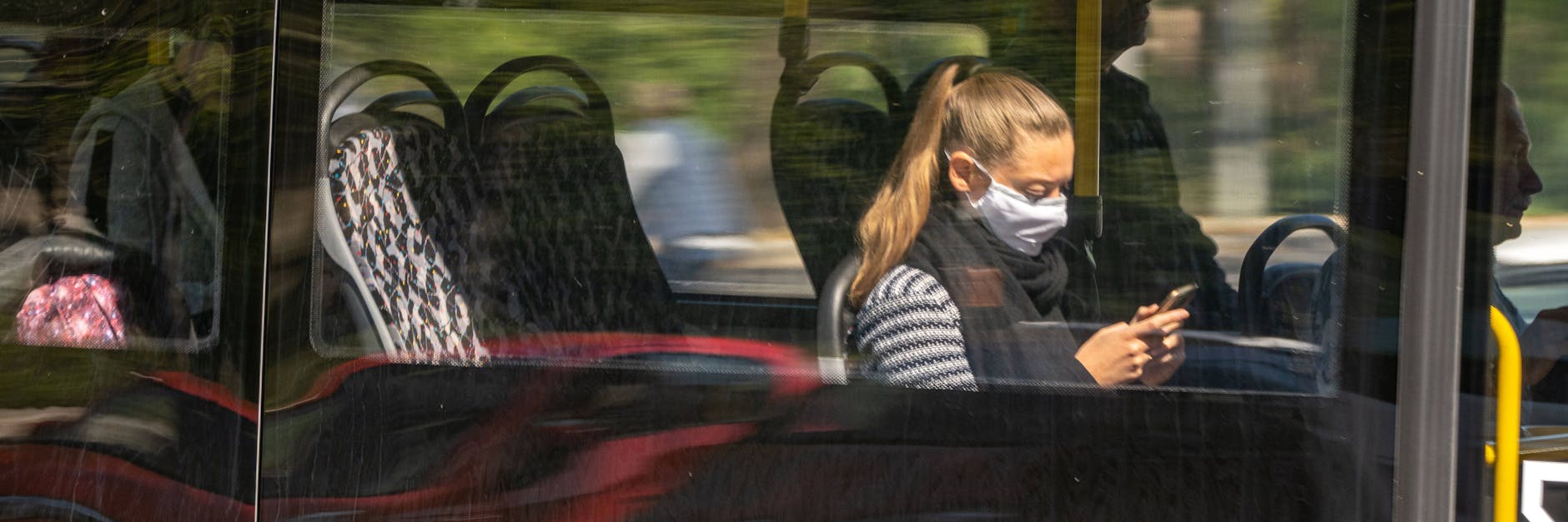 Eine Frau sitzt mit Mundschutz in einem Bus der BVG.