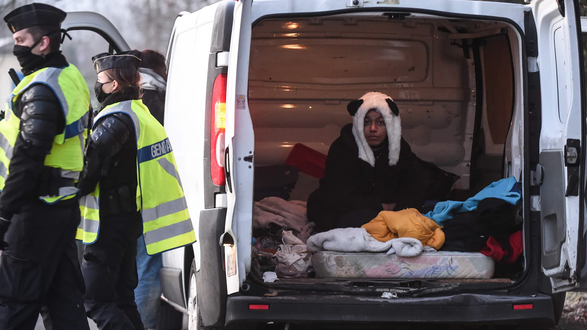 Eine Raverin mit Panda-Mütze sitzt in ihrem zum Schlafzimmer umgewidmeten Van.