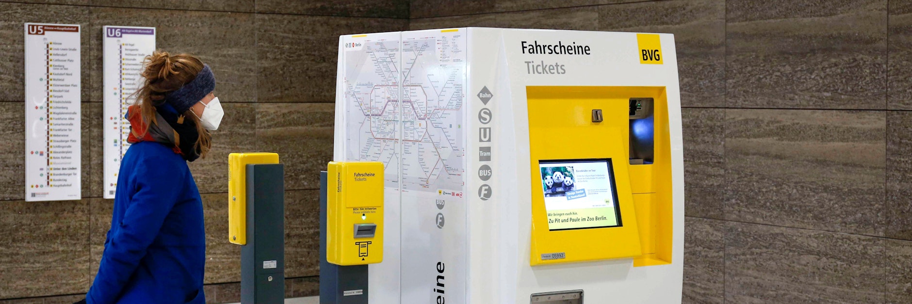 Eine Frau mit FFP2-Maske steht vor einem Automaten der BVG.