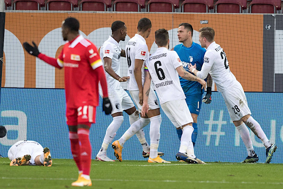 Während Sheraldo Becker bereits entnervt abdreht, bejubeln die Augsburger Spieler Ex-Union-Torwart Rafal Gikiewicz.
