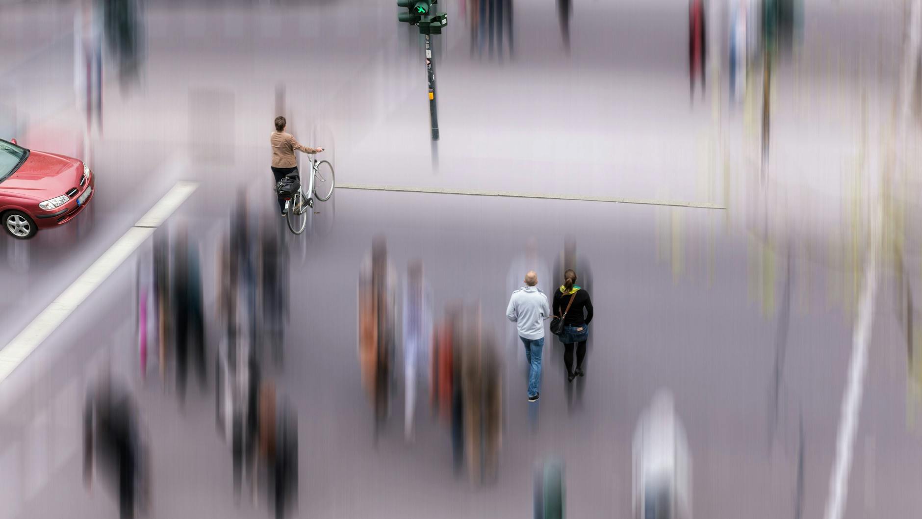 Fußgänger überqueren bei grüner Ampel eine Straße.