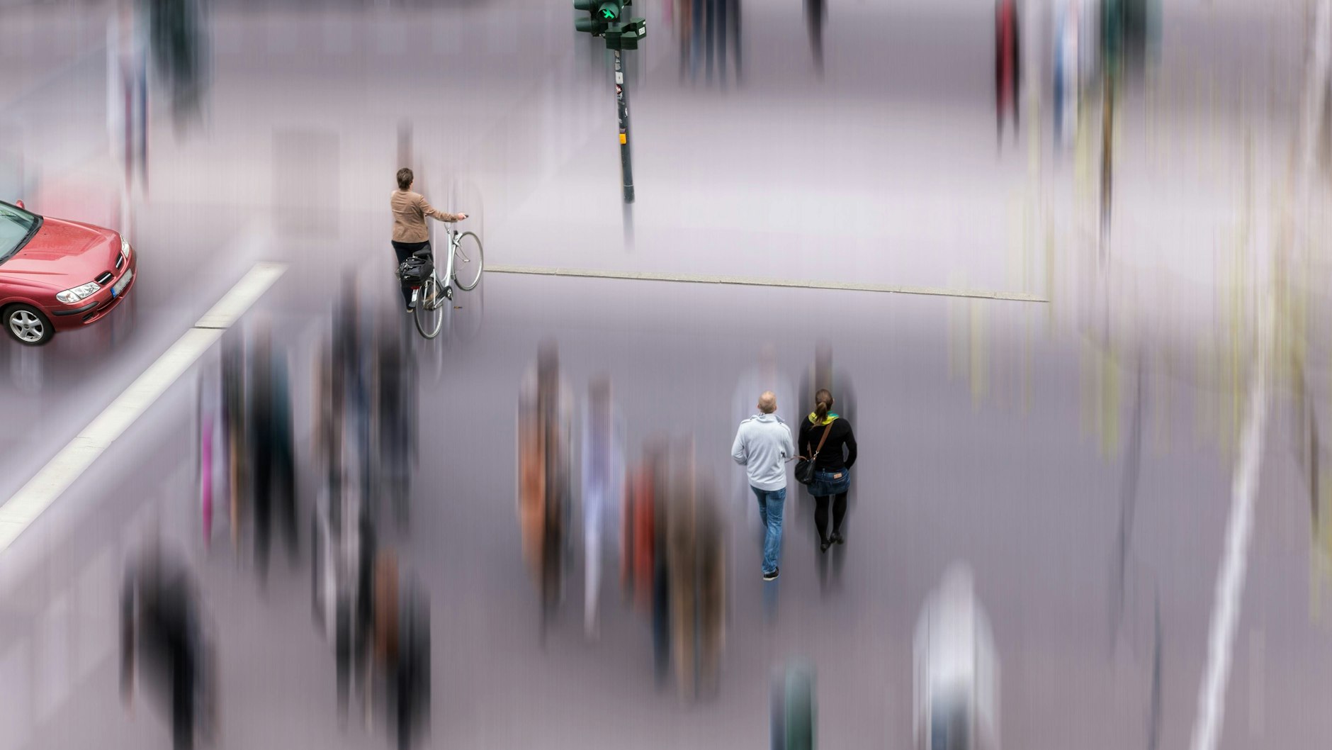 Fußgänger überqueren bei grüner Ampel eine Straße.