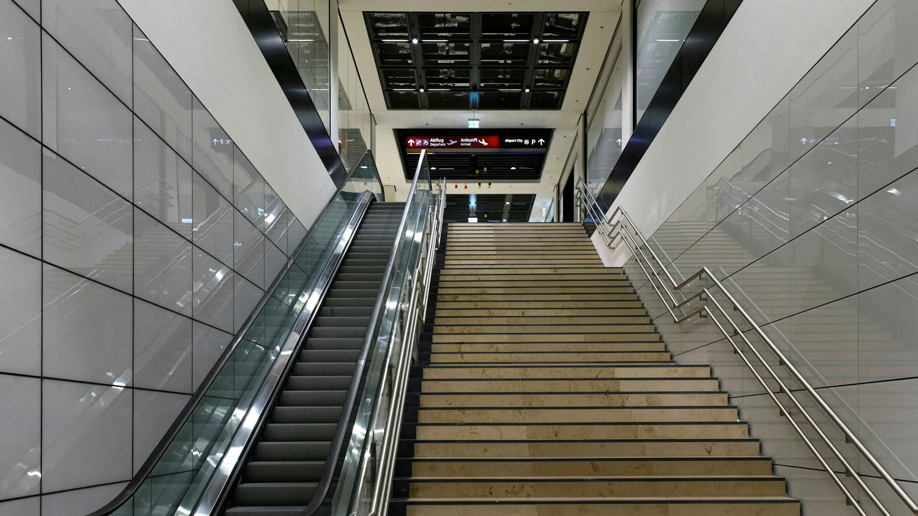 Im Flughafenbahnhof gibt es nur aufwärts führende Fahrtreppen. Ursprünglich sollten die Aufgänge breiter ausfallen, dann hätte es auch Platz für Fahrtreppen nach unten gegeben. Doch die Flughafengesellschaft, Bauherr des Bahnhofs, wollte sparen. 