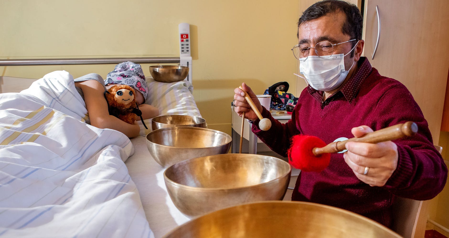 Der Musik- und Klangtherapeut Minas Suluyan hilft mit seinen Klangschalen einem schwerkranken Kind, sich zu entspannen.