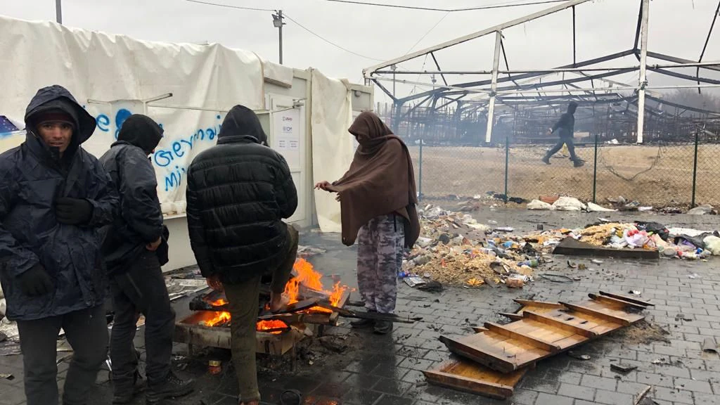 Geflüchtete wäremen sich an einem offenen Feuer.
