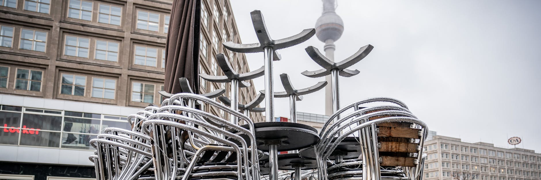 Stühle und Tische sind am weitgehend leeren Alexanderplatz in der Hauptstadt hochgestellt. Einige Händler wollen am Montag wieder öffnen, trotz Corona.