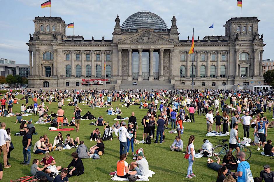 Die Ruhe nach dem Chaos am Sonntag: Berlinerinnen und Berliner warten auf die Wahlergebnisse auf der Wiese vor dem Reichstag.