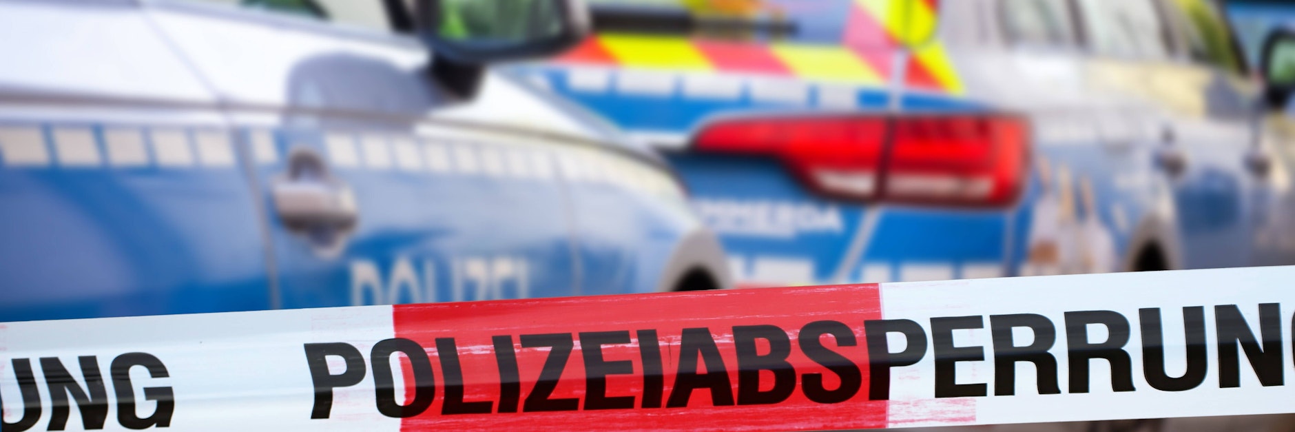 Eine Polizeiabsperrung mit Polizeiauto im Hintergrund (Symbolfoto)