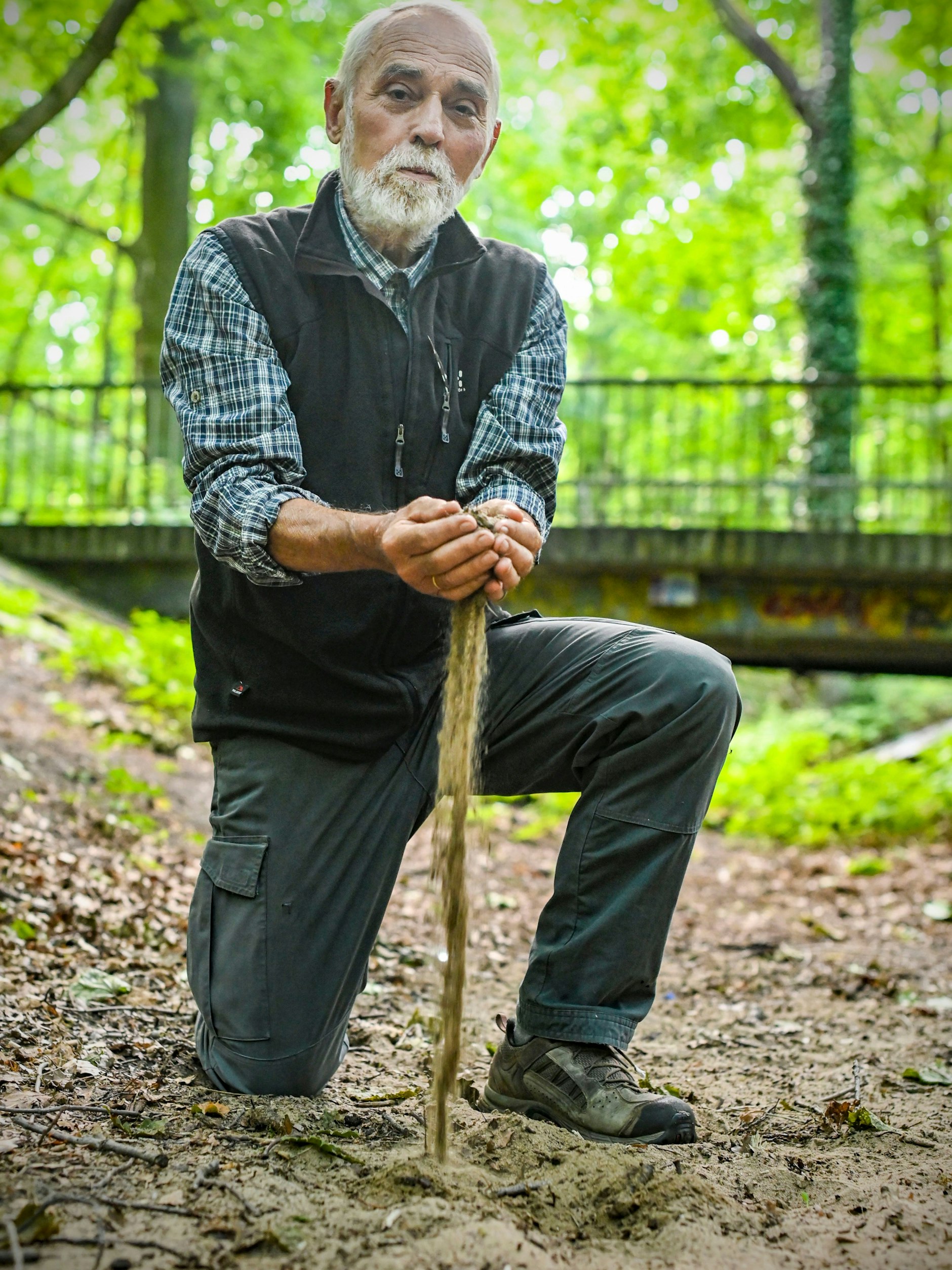 Eckhart Scheffler lässt Sand aus dem Fredersdorfer Mühlenfließ durch seine Hände rieseln.