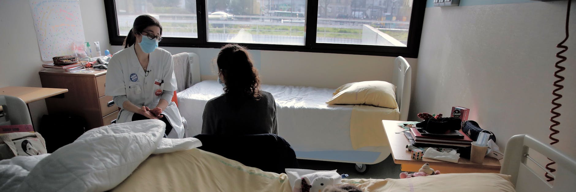 Eine Psychologin spricht mit einem Mädchen in ihrem Zimmer in der pädiatrischen Abteilung eines Krankenhauses.