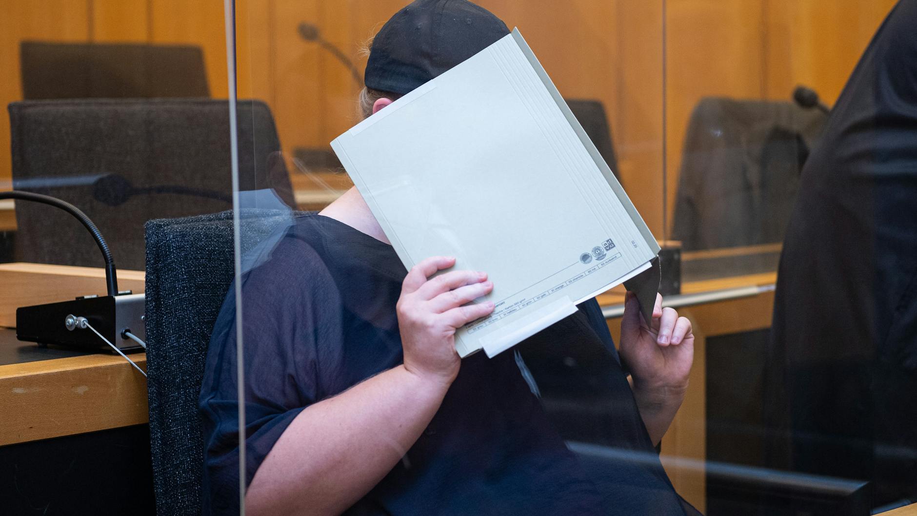 Zu Beginn des Prozesses im Missbrauchskomplex Münster sitzt die Mutter eines Opfers im Landgericht Münster und verdeckt ihr Gesicht mit einer Mappe.