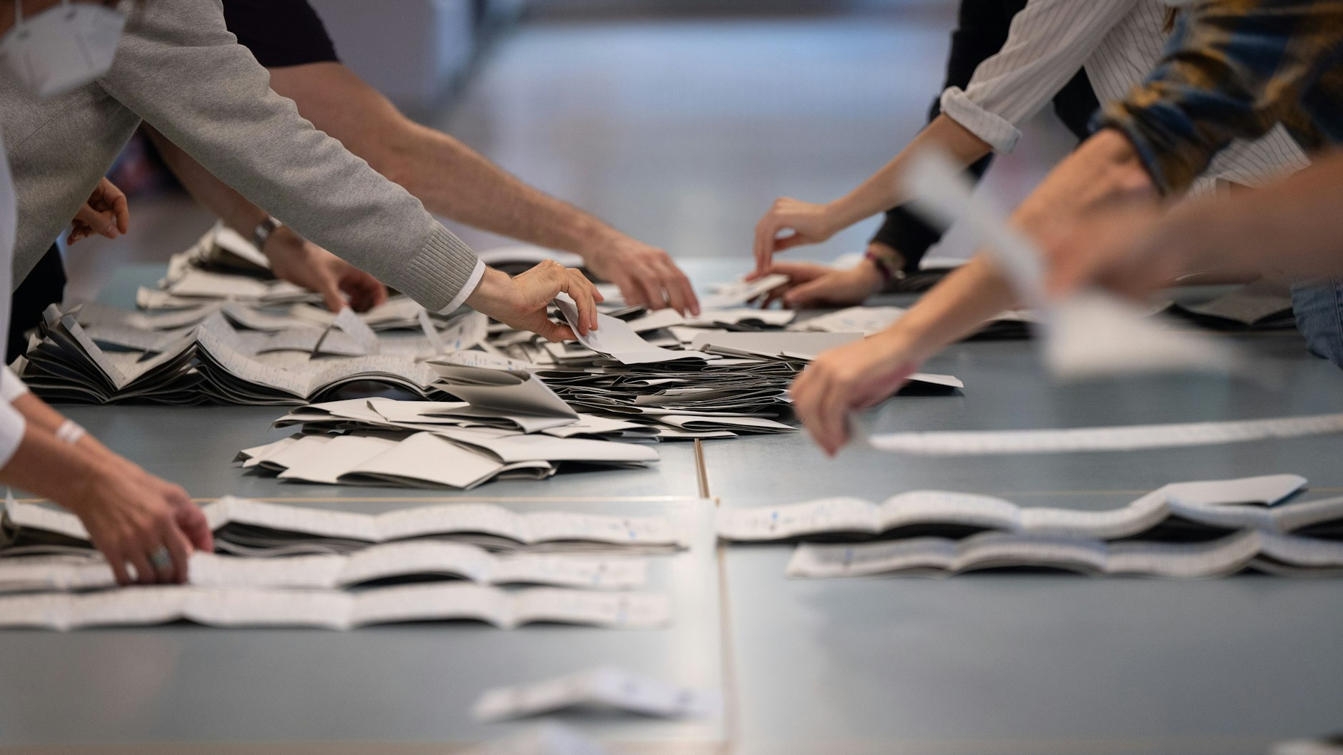 Wahlhelfer und Wahlhelferinnen zählen Stimmzettel für die Bundestagswahl. In Berlin soll es in 4,5 Prozent der Wahllokale Probleme mit falschen oder fehlenden Stimmzetteln gegeben haben. Wahlhelfer fehlten oder waren überfordert. Auch Minderjährige unter 18 Jahre sollen gewählt haben.