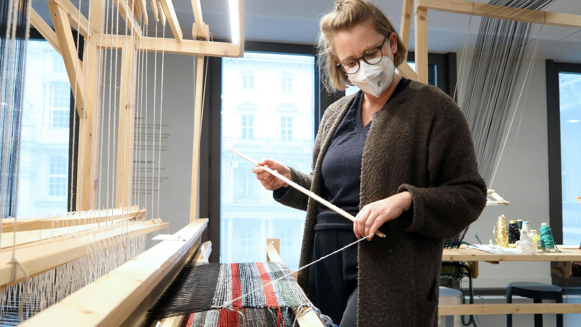 Im Humboldt-Forum gibt es das „Weltstudio“ mit diversen Kartografie-Möglichkeiten. KURIER-Redakteurin Stefanie Hildebrandt versucht sich am Webstuhl, die Farbe des Fadens zeigt, wie weit ihre Geburtsstadt von Berlin entfernt ist.