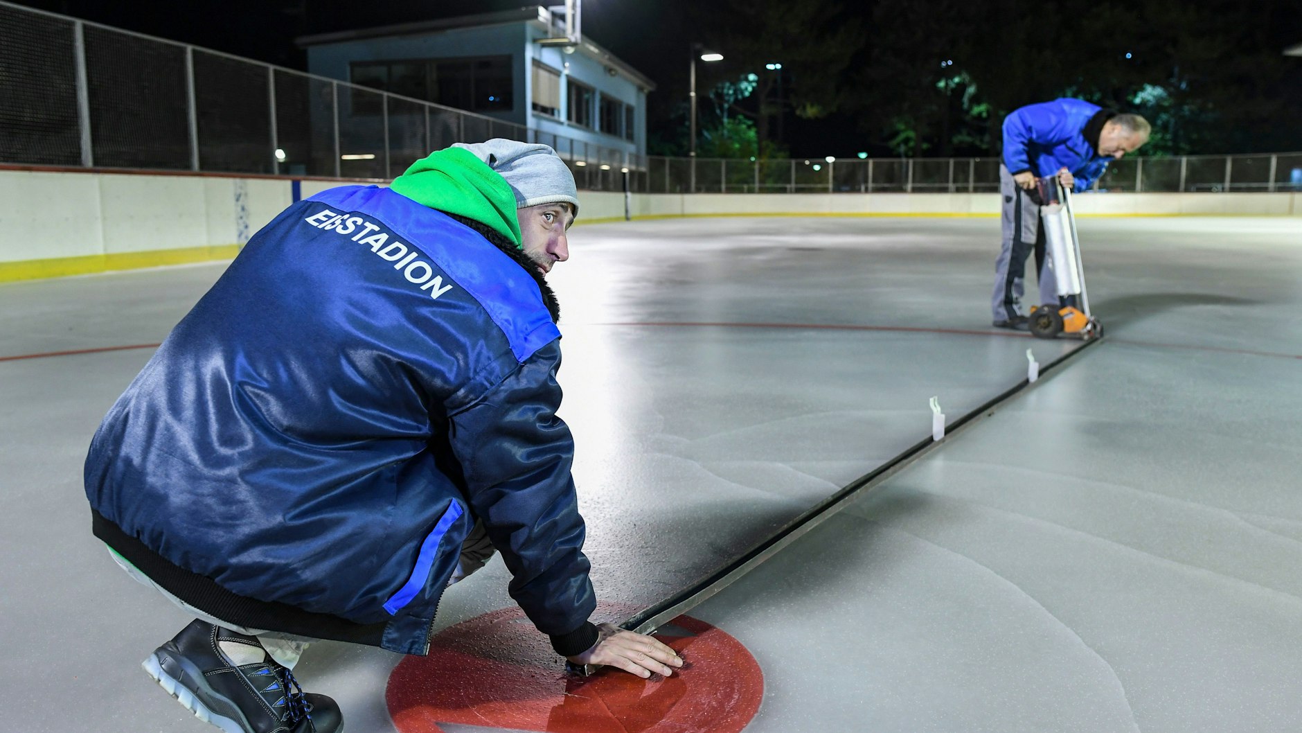 Die Männer vom Eisstadion Neukölln bauen nicht nur das Eis auf, sie bringen auch die Eishockey-Markierungen auf.