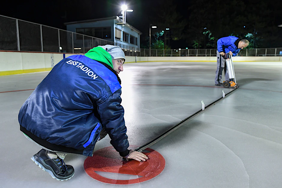 Die Männer vom Eisstadion Neukölln bauen nicht nur das Eis auf, sie bringen auch die Eishockey-Markierungen auf.