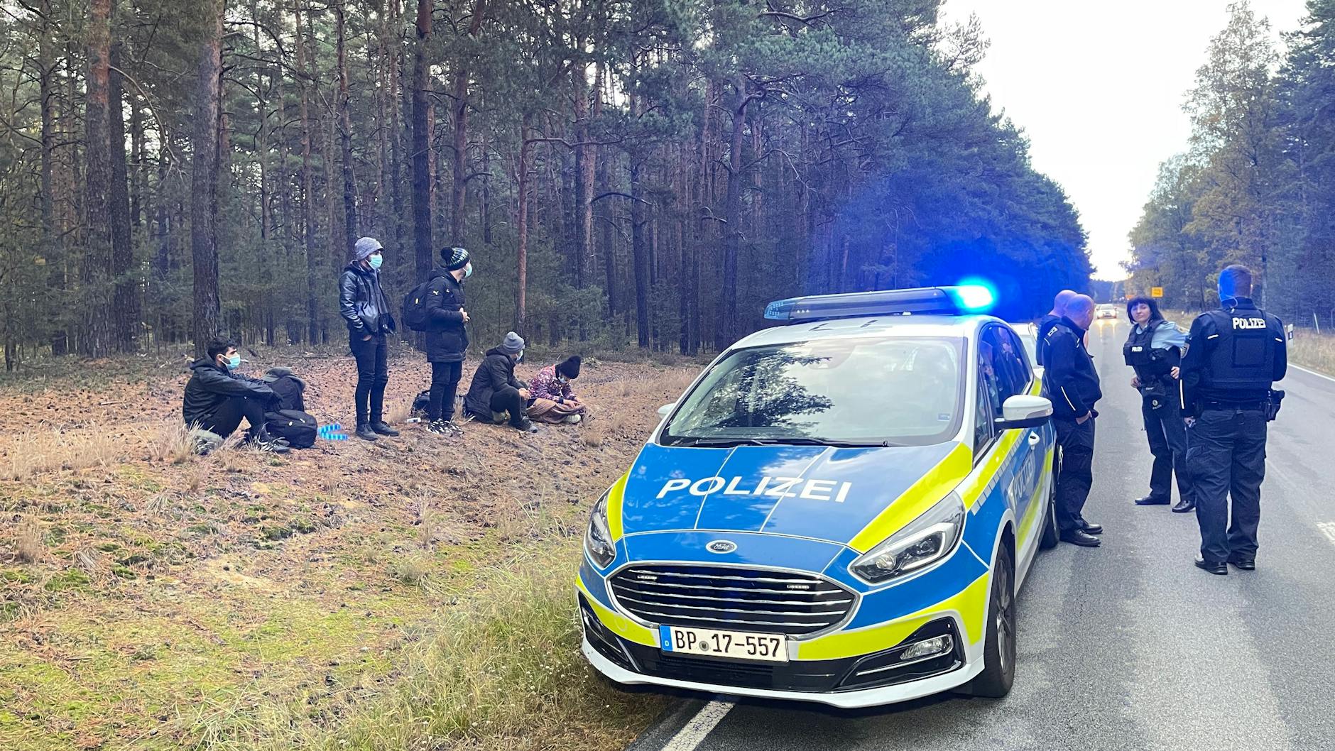 Bundespolizisten stehen neben einer Gruppe von Migranten, die zuvor über die deutsch-polnische Grenze gelangt waren. 