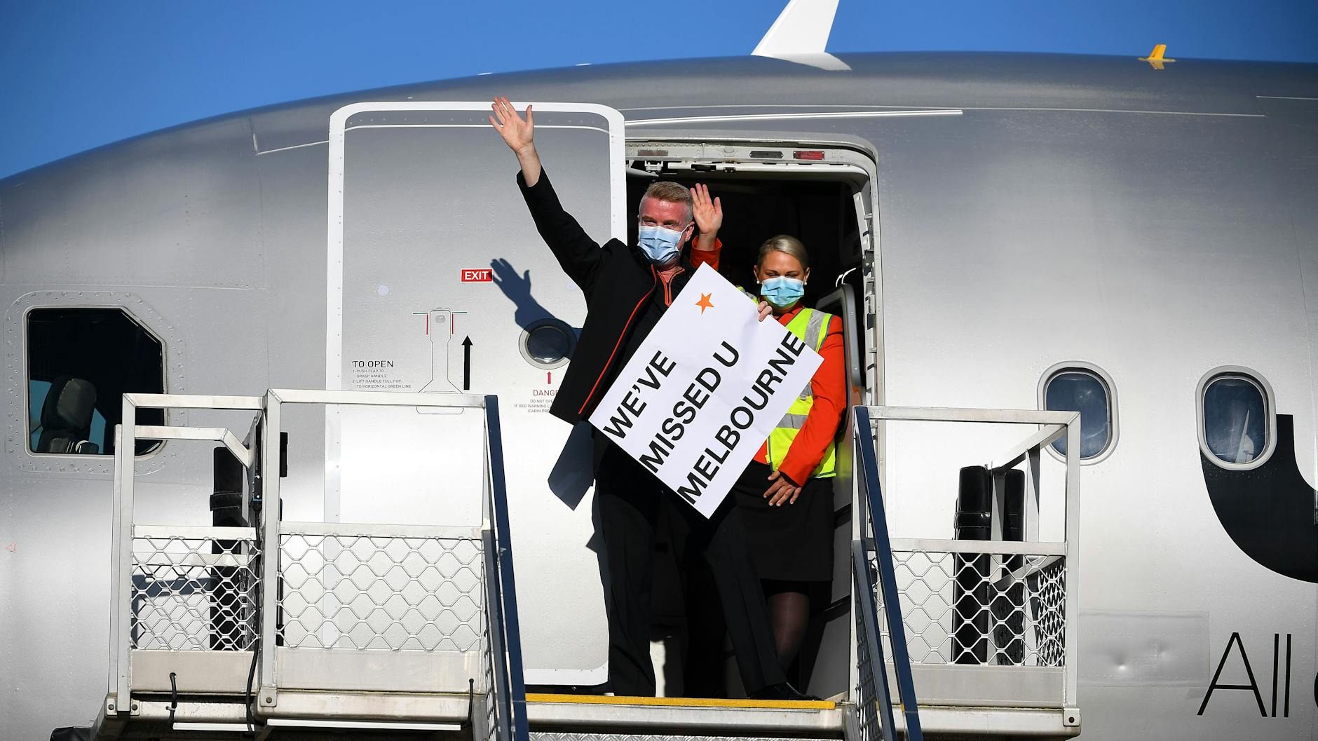 Crewmitglieder winken und halten ein Schild: „Wir haben dich vermisst, Melbourne.“