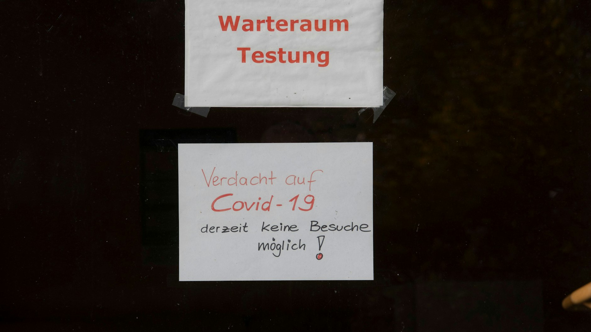 "Warteraum Testung" und "Verdacht auf Covid-19 derzeit keine Besuche möglich!" steht auf Zetteln an einer Scheibe in dem Seniorenheim am Werbellinsee.