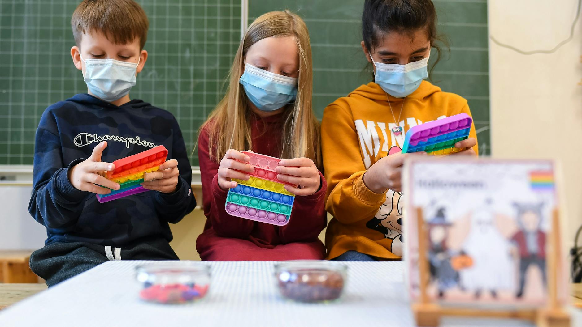 In einem Klassenzimmer einer Bielefelder Grundschule spielen Lorena, Ava und Theodor (v. r. n. l.) mit Pop-Its. Ein wahrer Hype um die Silikonteile ist im Gang.