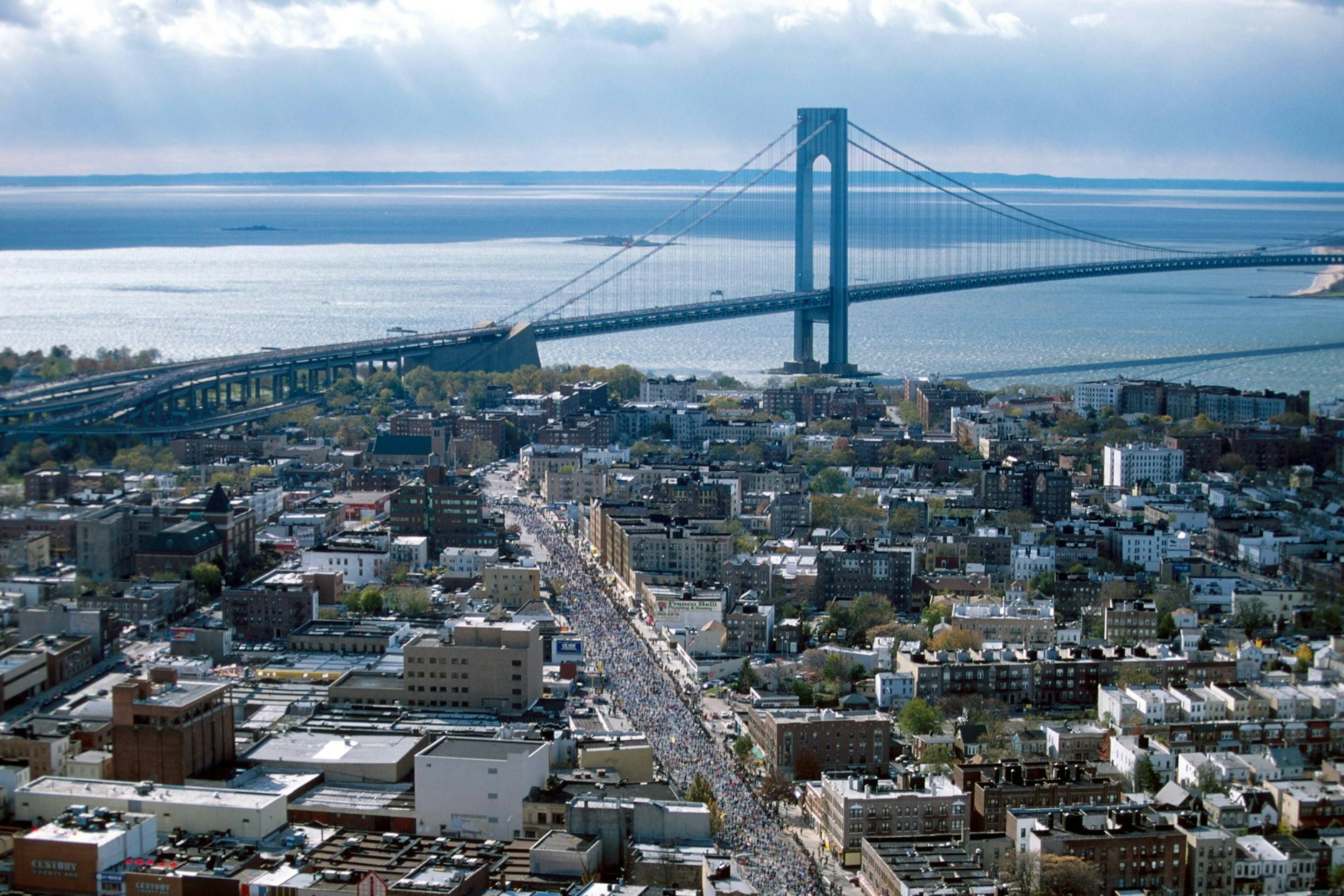 Marathonläufer in den Straßen von Staten Island, im Hintergrund die Verrazano Bridge.<br>