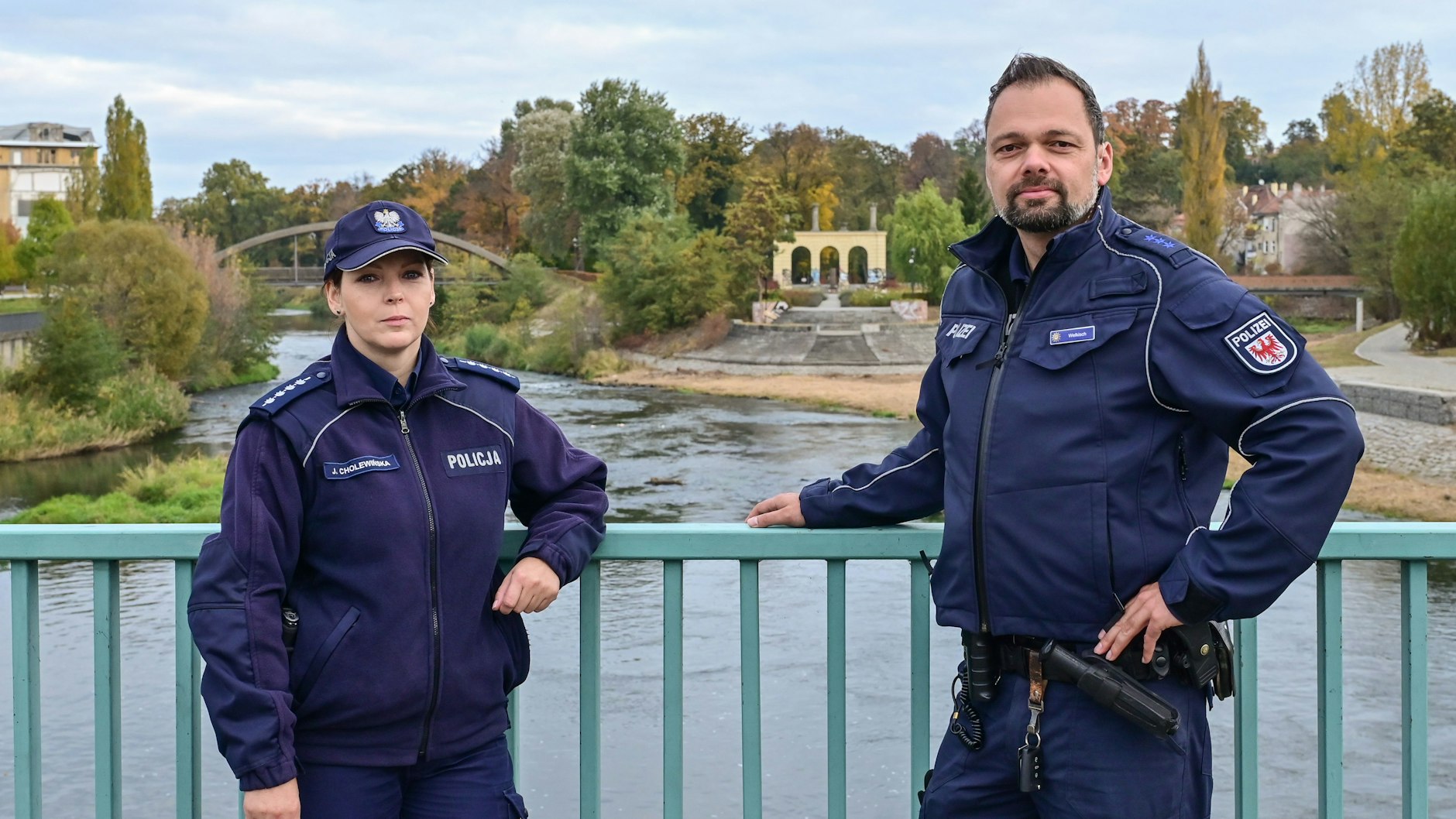 Die Polizisten Julita Cholewińska und Holger Welkisch auf der Stadtbrücke über die Neiße. Im Hintergrund&nbsp; die Reste des Ende 1945 abgebrannten Gubener Theaters.&nbsp;