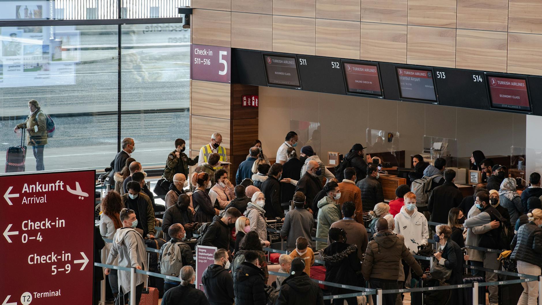 Reisende am Flughafen BER vor einem Check-in-Schalter