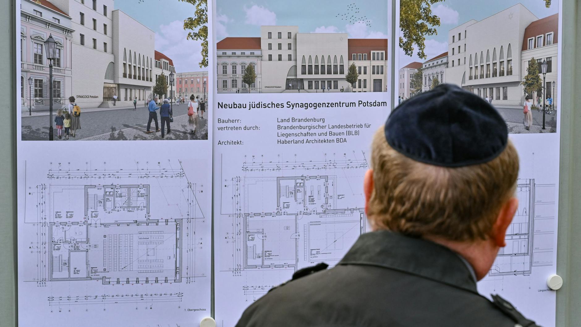Ein Mann mit Kippa betrachtet Computerskizzen der künftigen Synagoge.