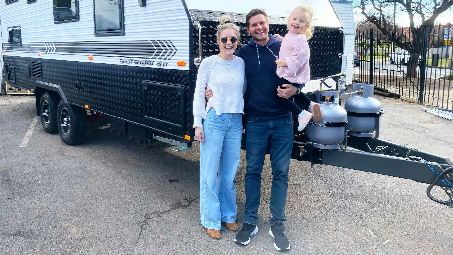 Sarah Excell, ihr Mann Sam und ihre gemeinsame Tochter Eva stehen vor ihrem Wohnwagen in Adelaide. Ein Schicksalsschlag brachte die kleine Familie zum Umdenken.