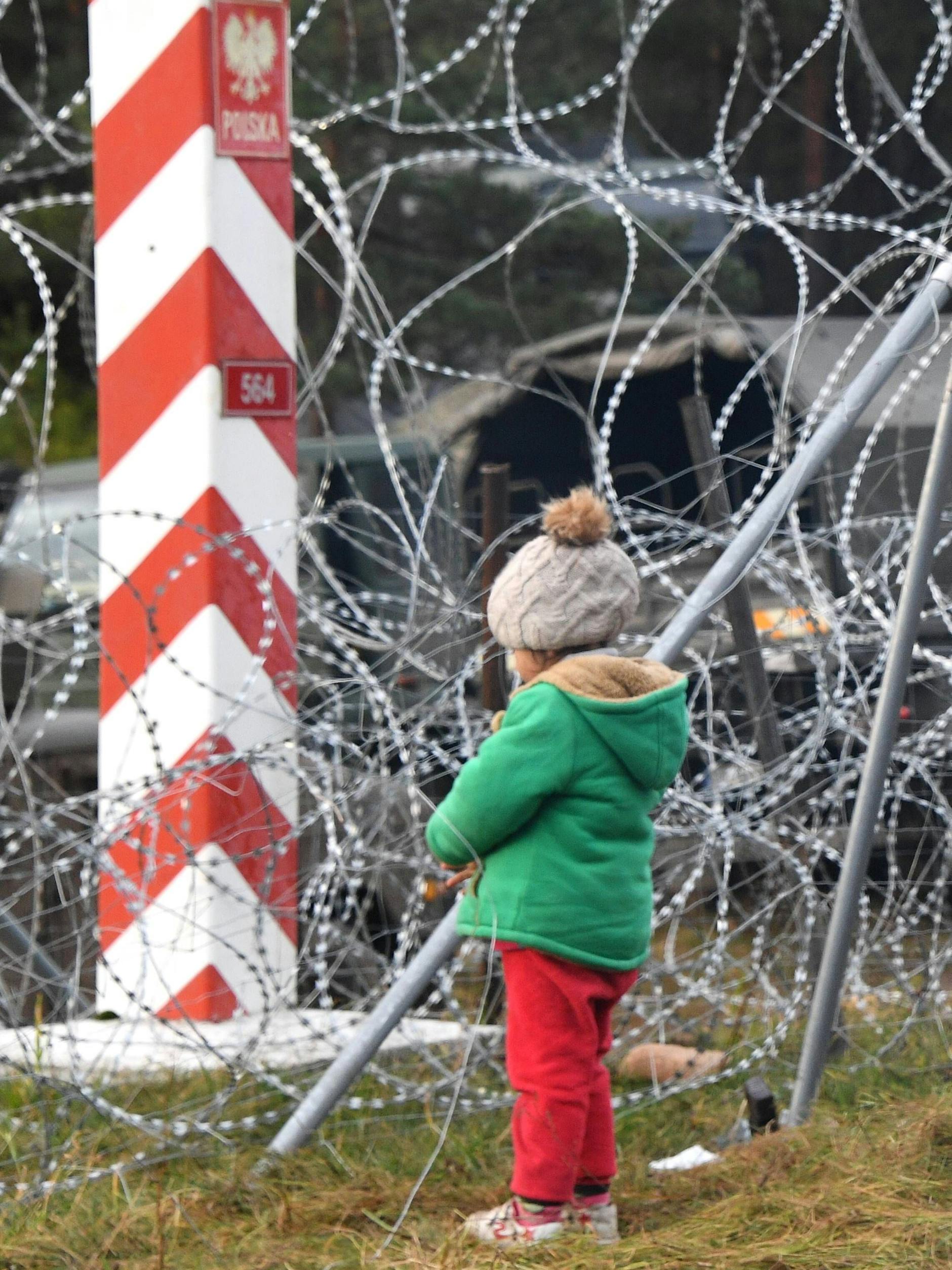 Ein Kind steht vor dem Stacheldrahtverhau, den polnische Grenzer errichtet haben.