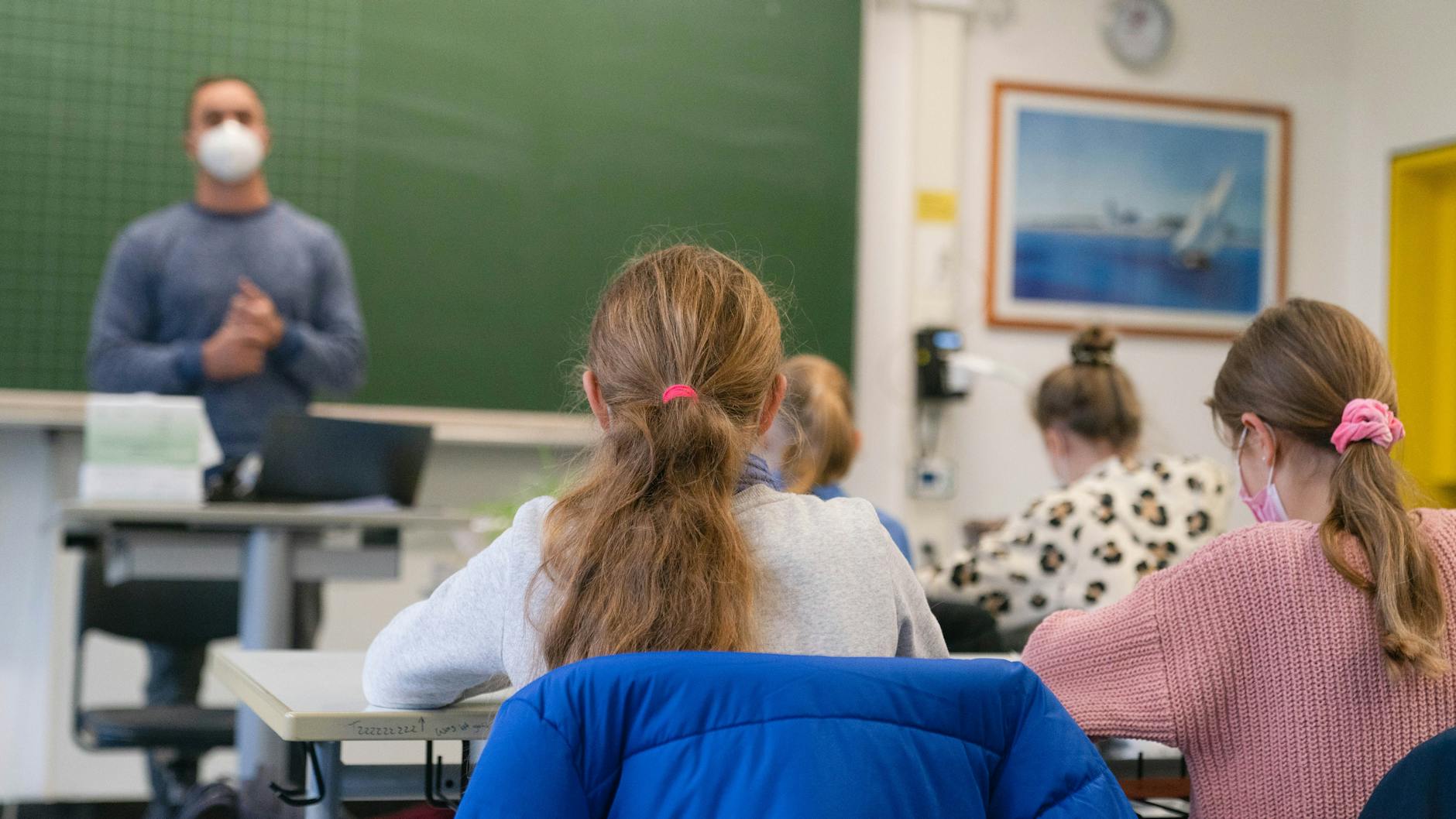 Schülerinnen sitzen mit Mund-Nasen-Schutz im Klassenzimmer (Symbolbild). Um das künftig zu vermeiden, fordert der Brandenburger Landeselternrat tägliche Corona-Tests. 