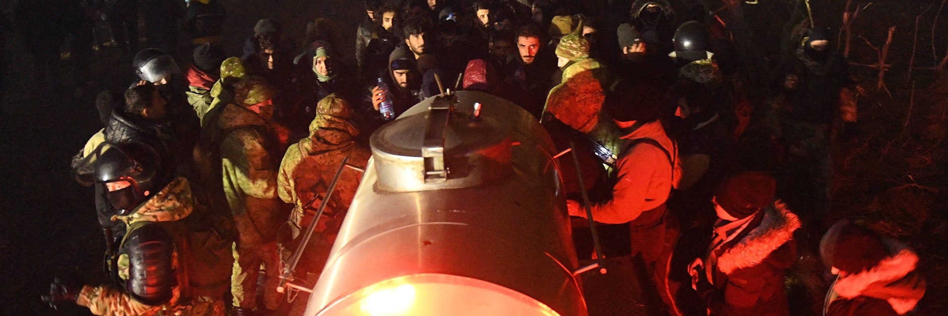Migranten versammeln sich nachts um einen Trinkwassertank, den Belarus an die polnische Grenze geschafft hatte.