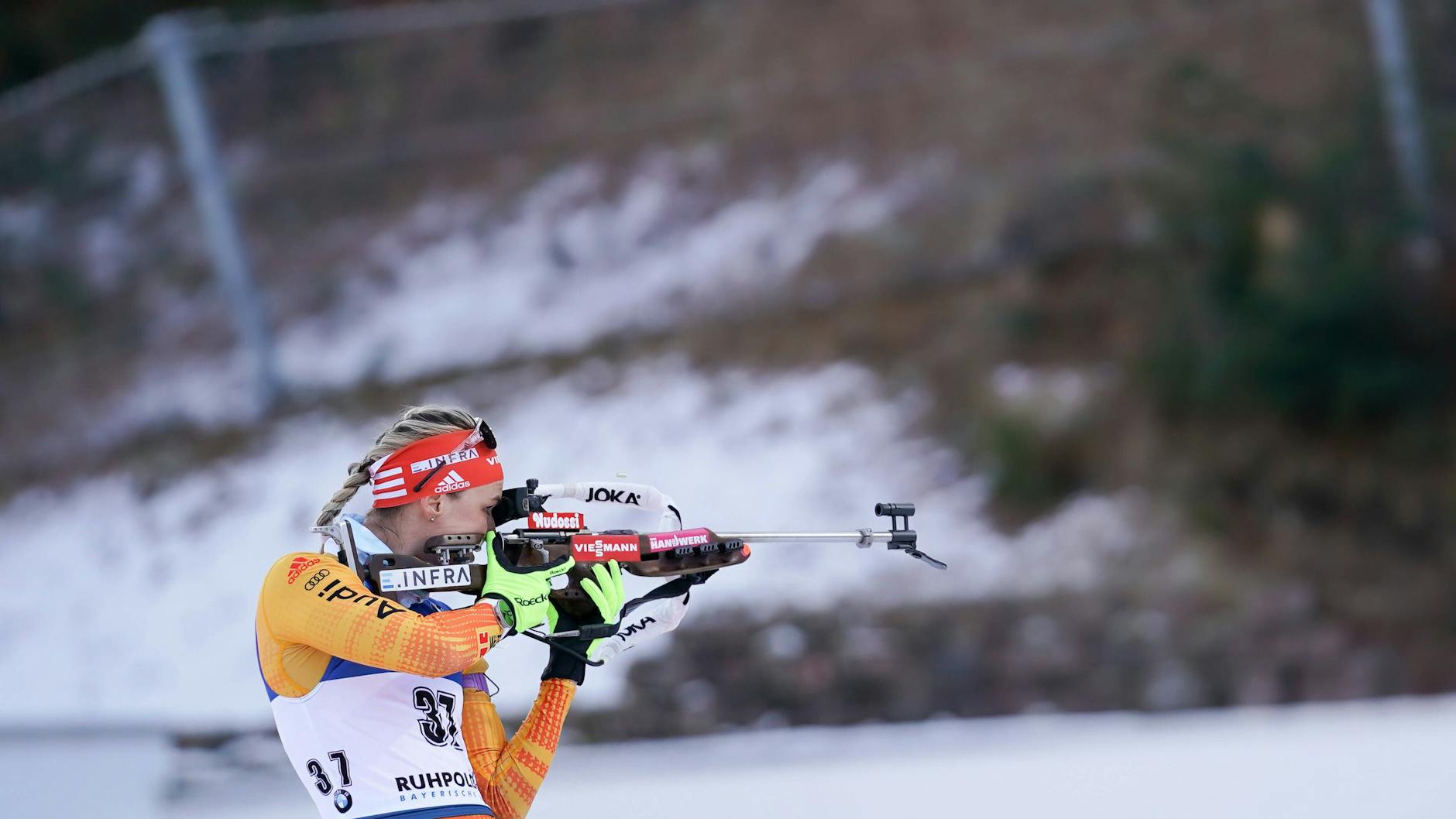 Biathlon-Athletin Denise Herrmann am Schießstand in Oberhof. Die Strecke ist beschneit, alles drumherum ist grün.