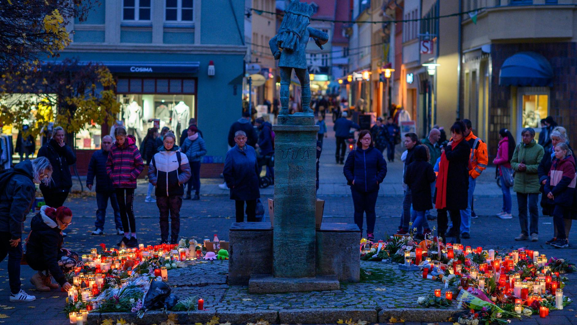 Blumen, Kerzen, Bilder und Stofftiere liegen am Holzmarkt in Aschersleben um ein Denkmal. Seit dem Vormittag kamen Menschen in die Innenstadt, um dort der getöteten 14-Jährigen zu gedenken und um Blumen niederzulegen oder Kerzen zu entzünden. 