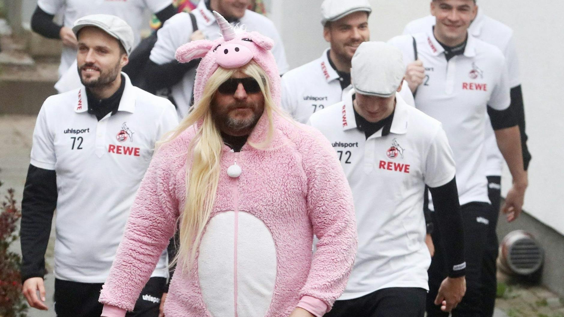 Steffen Baumgart kommt als rosa Einhorn-Schwein auf den Trainingsplatz. Sein Trainer-Team hat sich als er selbst verkleidet.