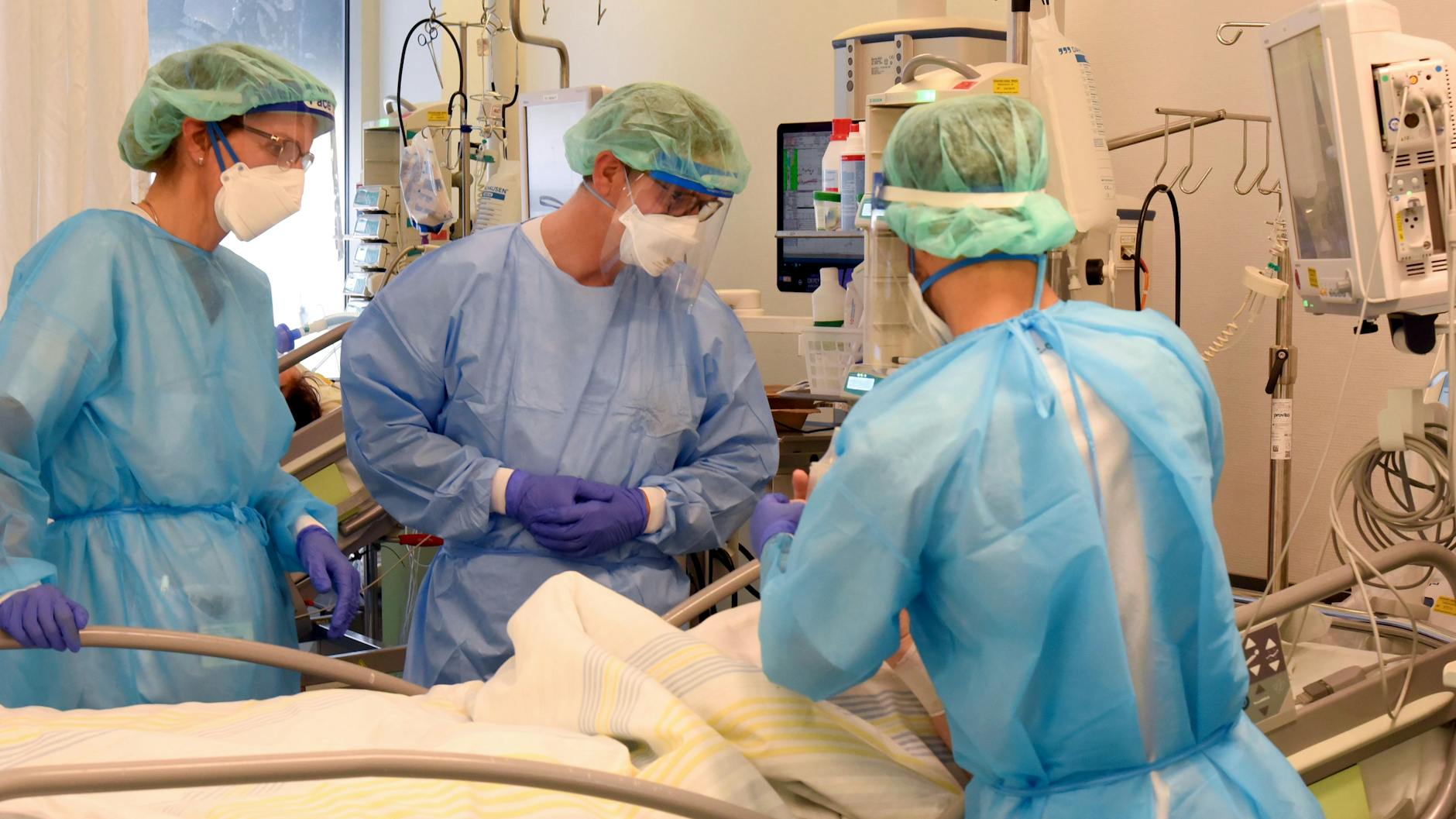 Klinik-Mitarbeiter am Bett eines schwerkranken Patienten auf einer Covid-Station. 