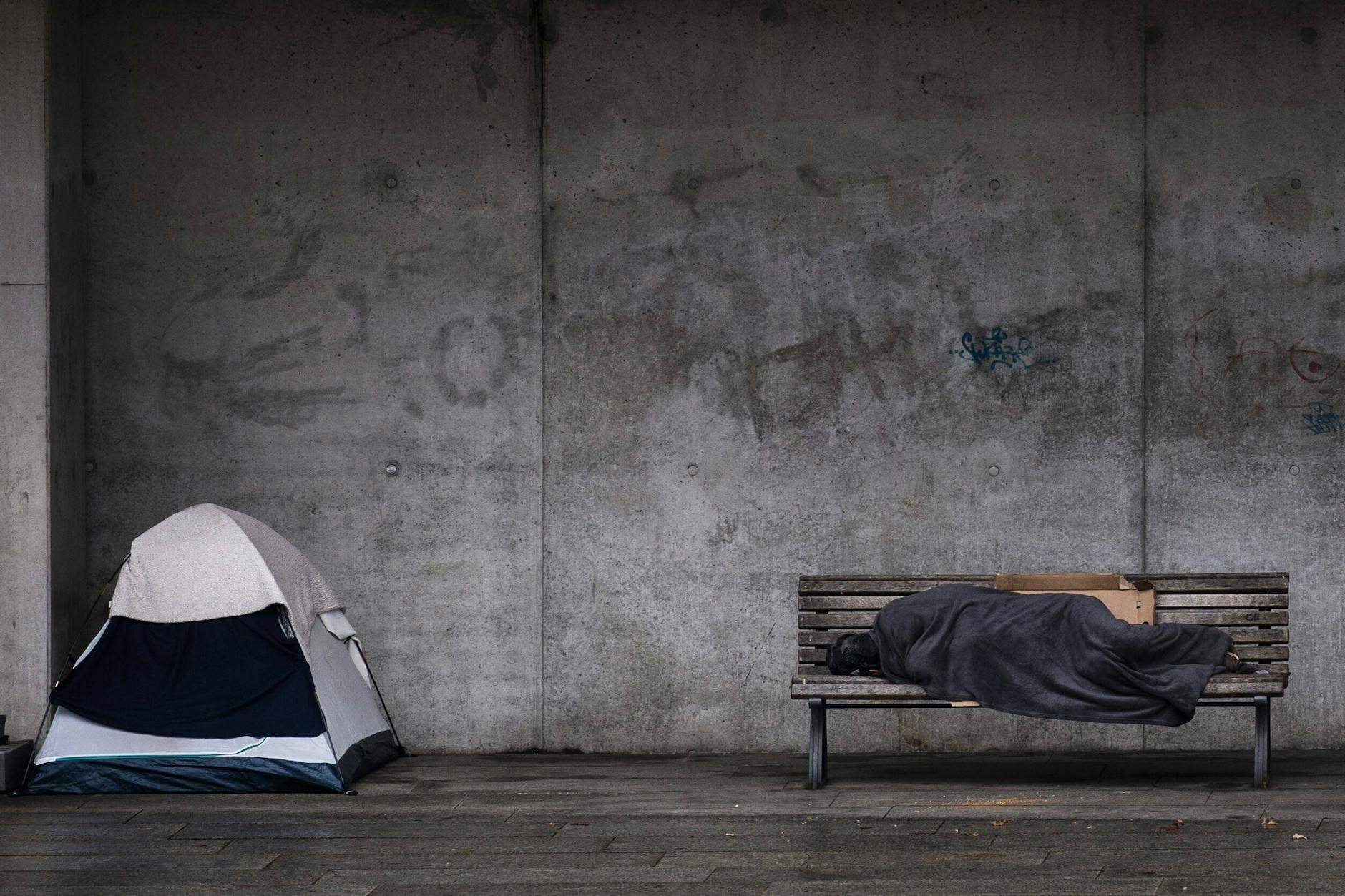 Ein Obdachloser schläft auf einer Bank in Berlin.