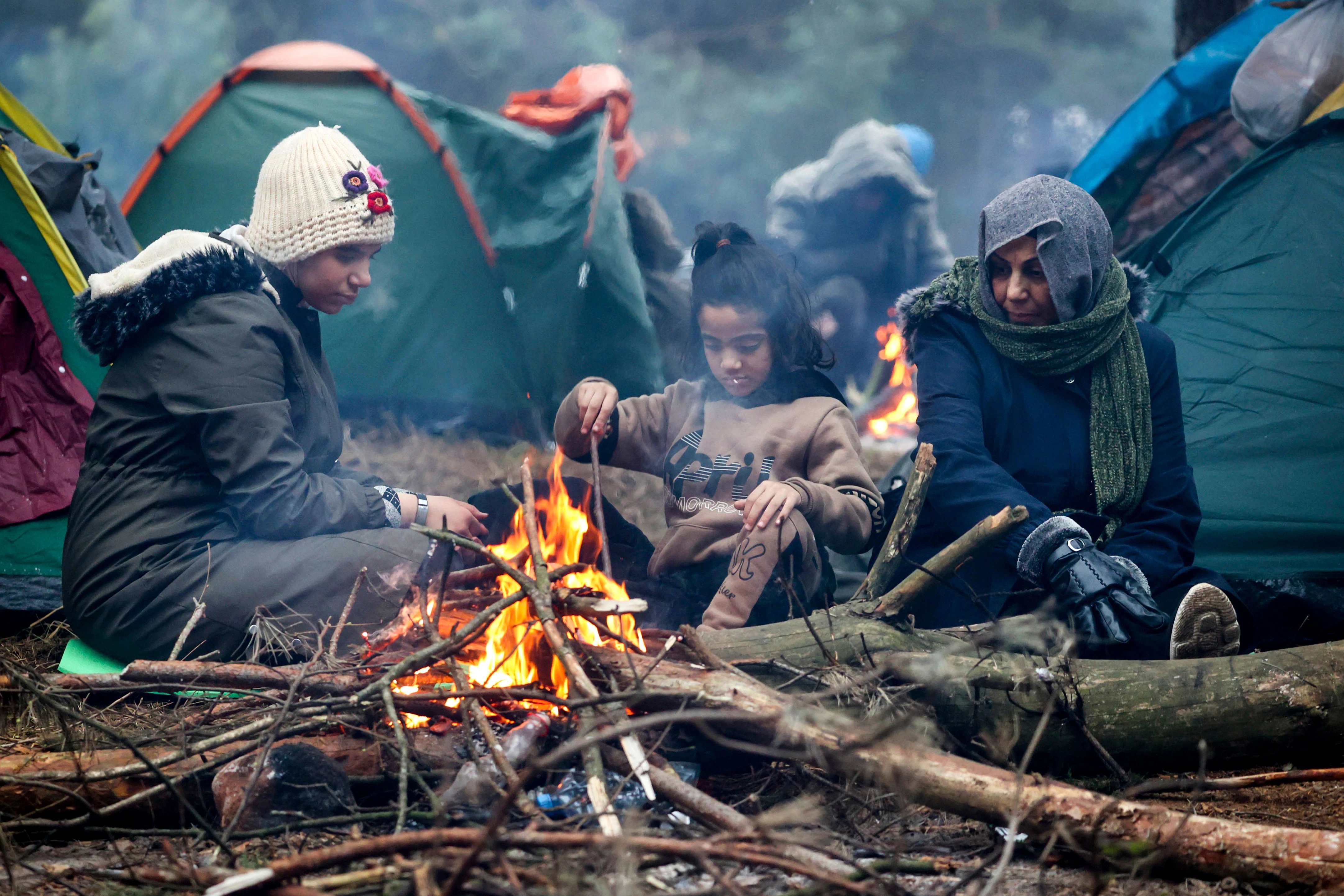 Migranten versammeln sich an der belarussisch-polnischen Grenze an einem Feuer, um sich zu wärmen.&nbsp;