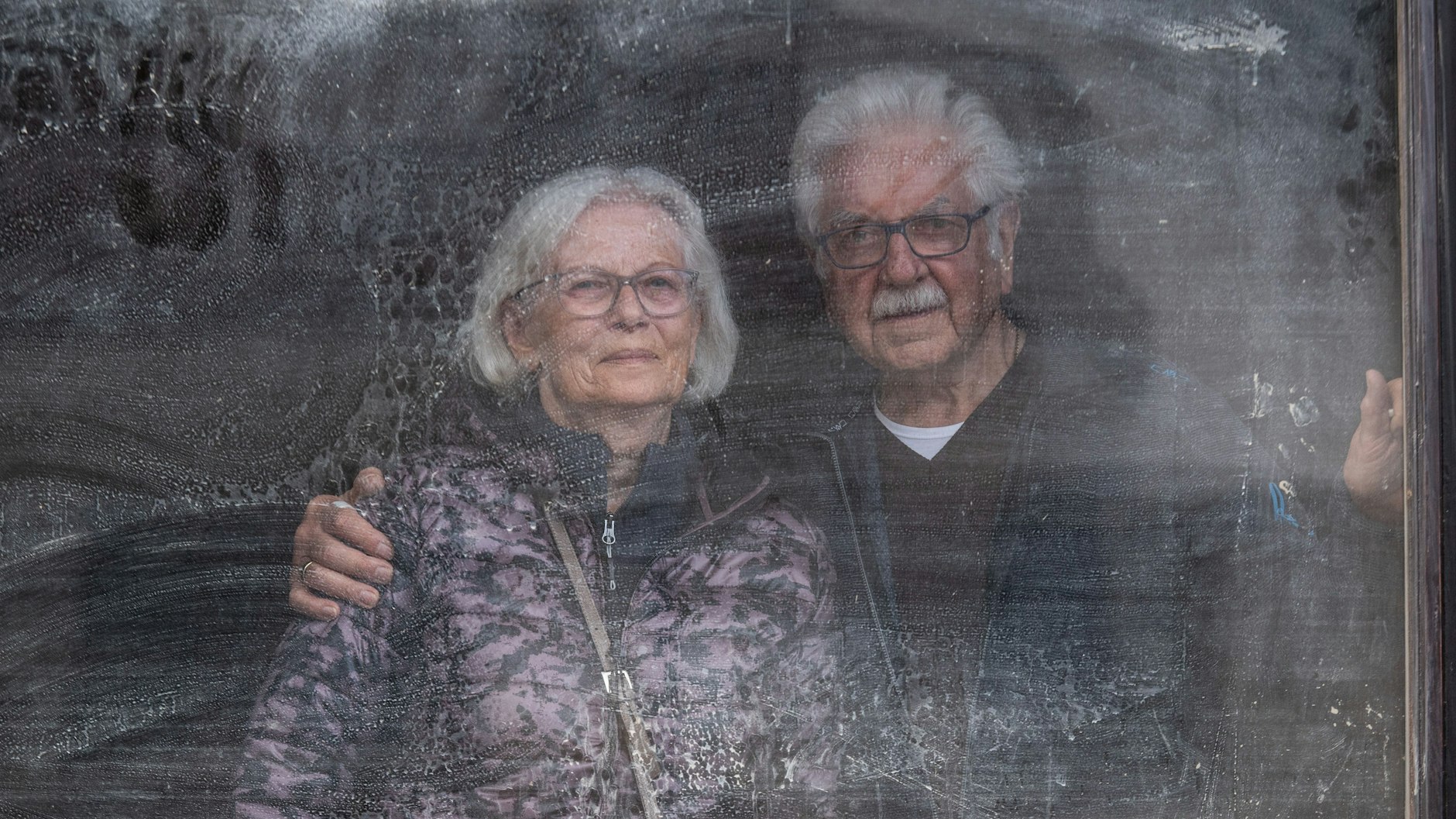 Elfriede und Gerd Gasper blicken aus dem noch immer mit Schlamm beschmierten Fenster ihres von der Flut zerstörten Hauses auf die Trümmer von Altenahr im Oktober 2021.