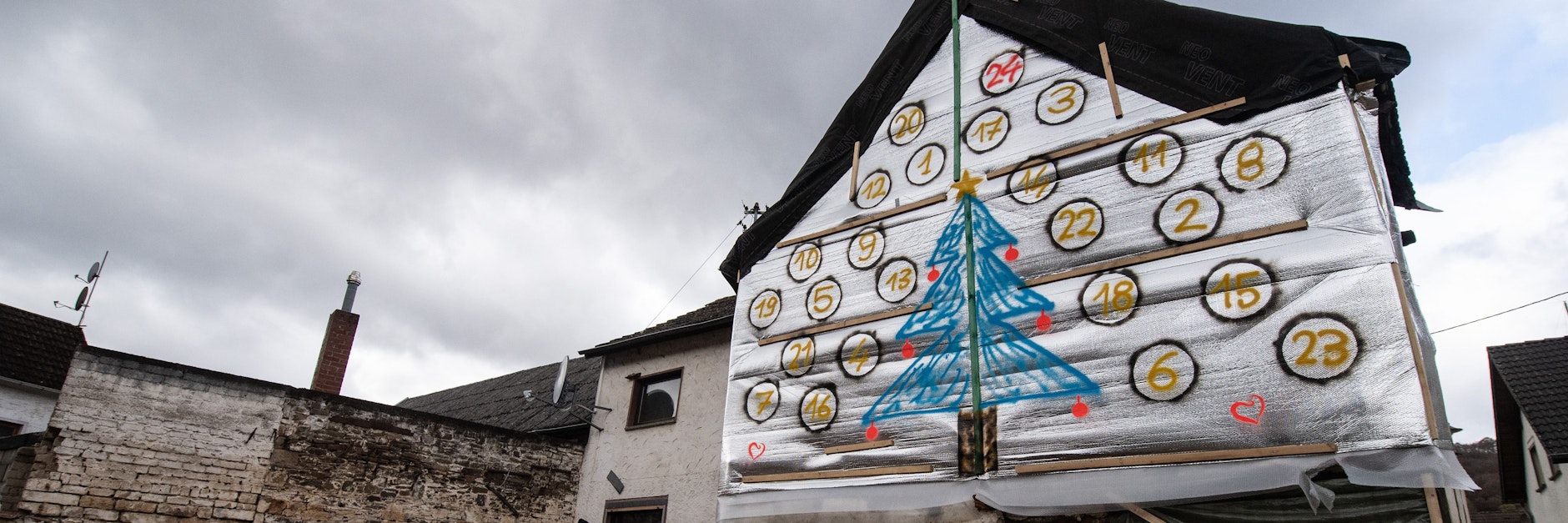 Jemand hat einen Adventskalender auf die Schutzplane eines von der Flut stark beschädigten Hauses in Insul gezeichnet. Auch Monate nach der Flutkatastrophe kehrt das Alltagsleben in die zerstörten Orte im Ahrtal nur sehr zögerlich zurück. 