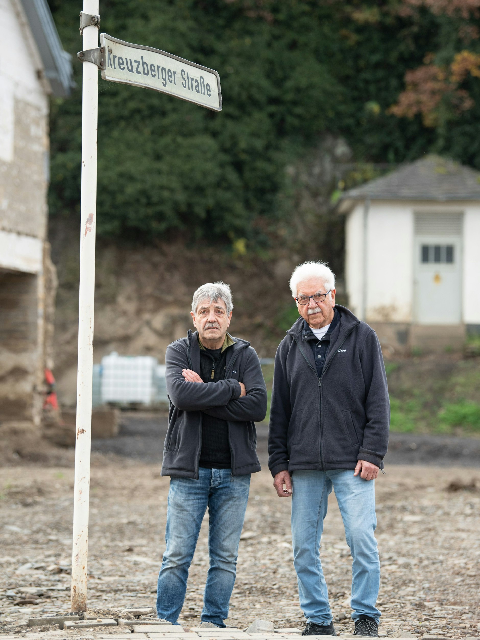 Die Brüder Bernd (li.) und Gerd Gasper stehen in Altenahr-Altenstadt an auf einer Brachfläche, auf der bis vor wenigen Wochen ihr Elternhaus gestanden hat.&nbsp;