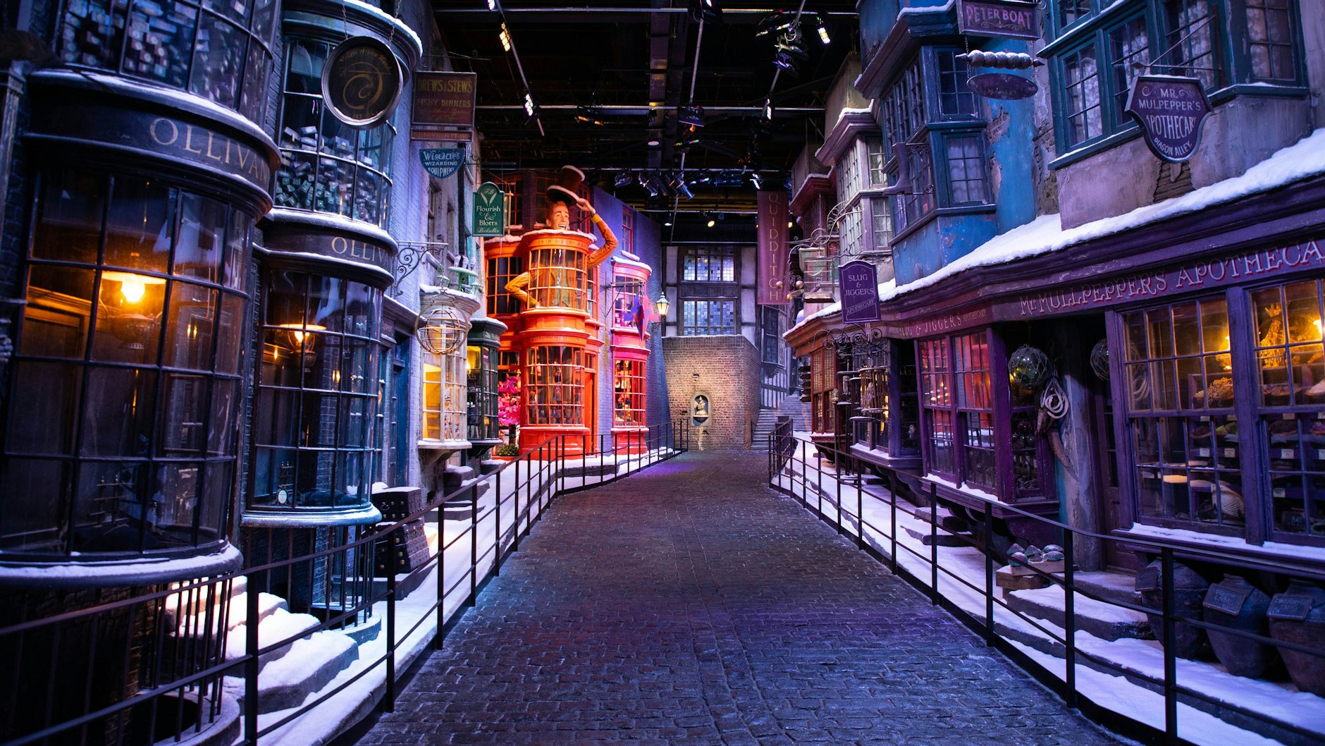 Ein Blick auf die Winkelgasse (Diagon Alley) der Warner Bros. Studios Tour London des jährlich wiederkehrenden „Hogwarts in the Snow“, bei dem die Schaufensterfronten und Bürgersteige der Winkelgasse mit Kunstschnee bedeckt sind.