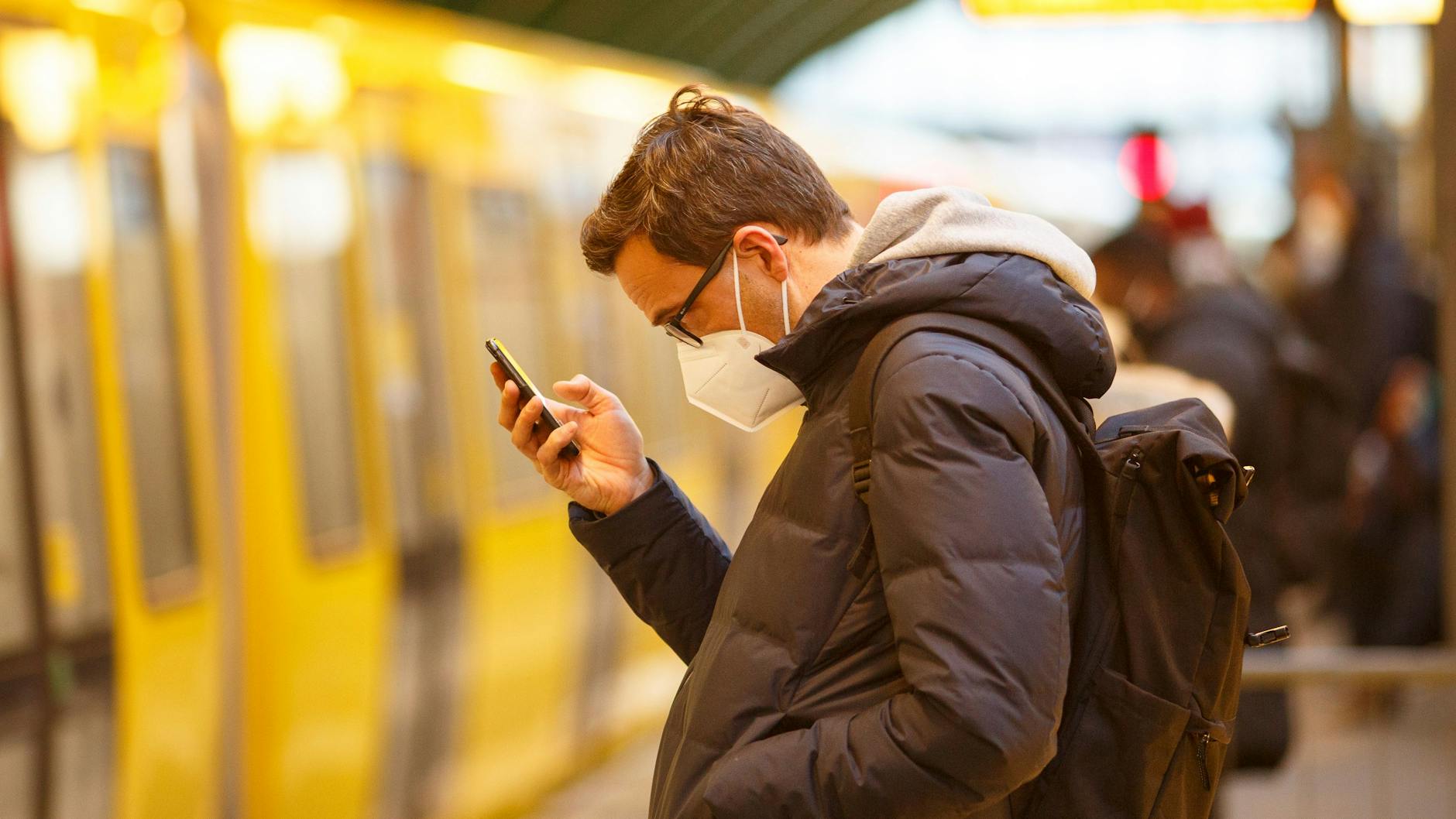 Hoffentlich geimpft, genesen oder negativ getestet. Ein Fahrgast schaut auf einem Berliner U-Bahnhof auf sein Handy. Immerhin: Laut Gesetz reichen bald wieder medizinische Masken aus.