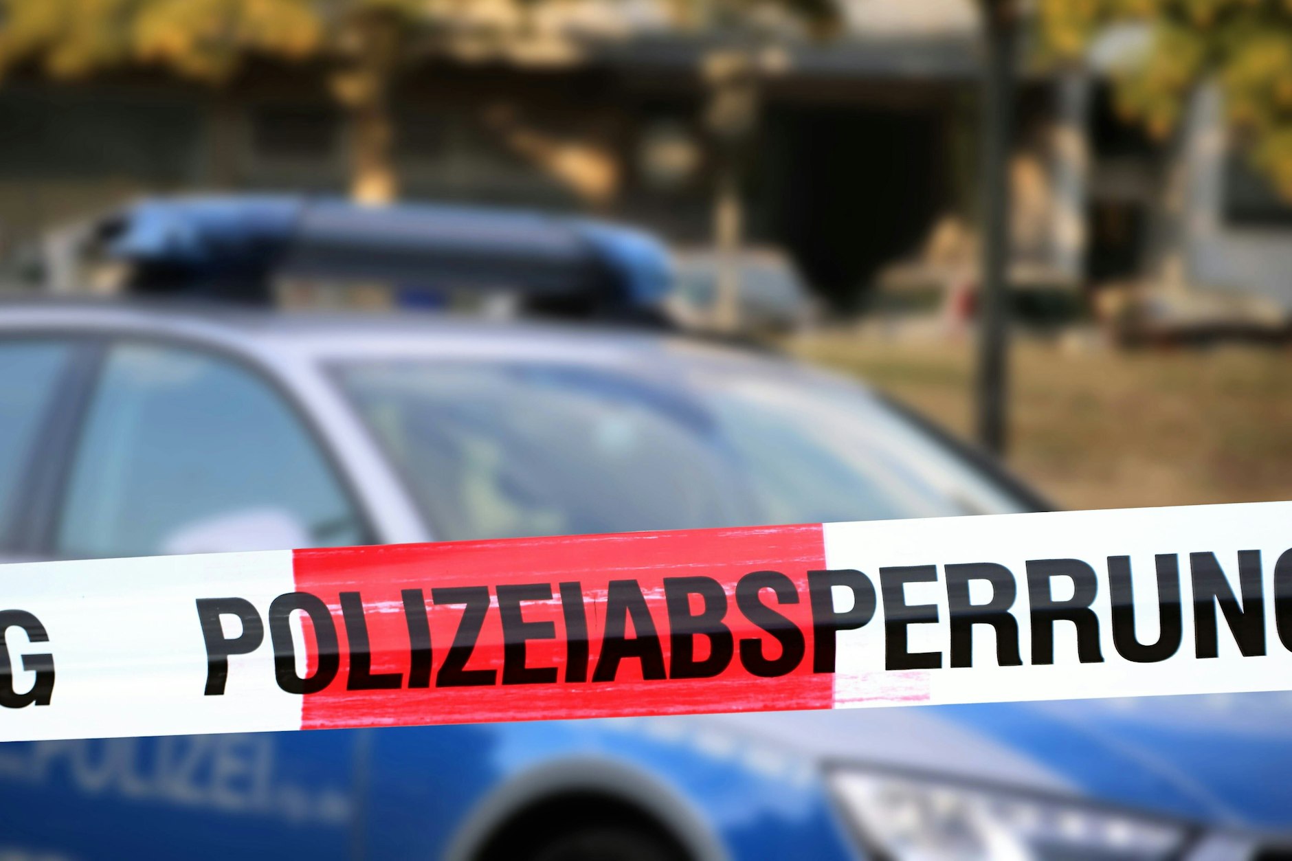 Ein Einsatzwagen der Polizei steht an einem abgesperrten Tatort.