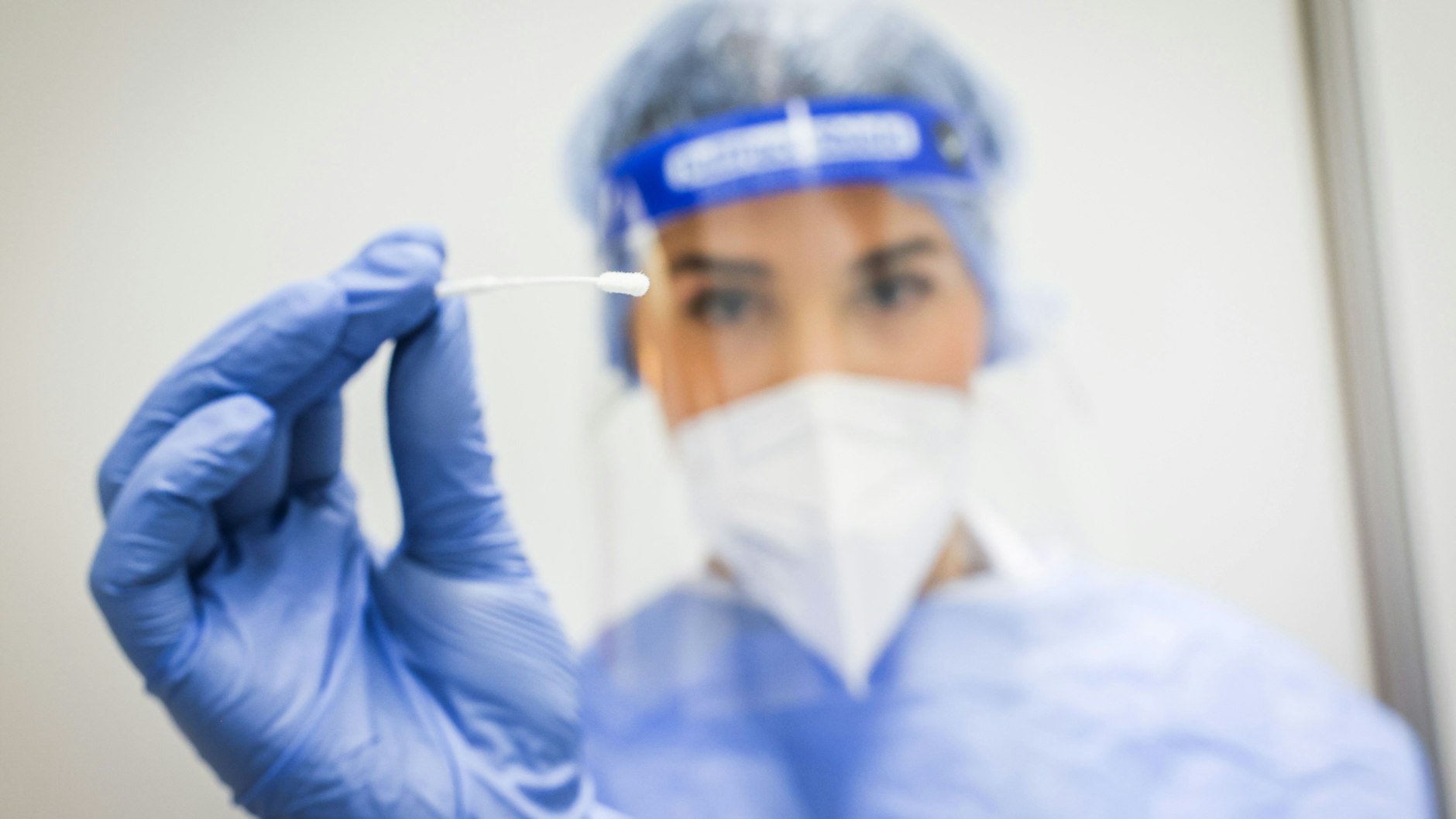 Eine Mitarbeiterin im Corona-Testzentrum hält ein Teststäbchen für einen Nasen-Rachen-Abstrich. Wer sich künftig für den Job nicht wenigstens testen lässt, dem drohen harte Konsequenzen.